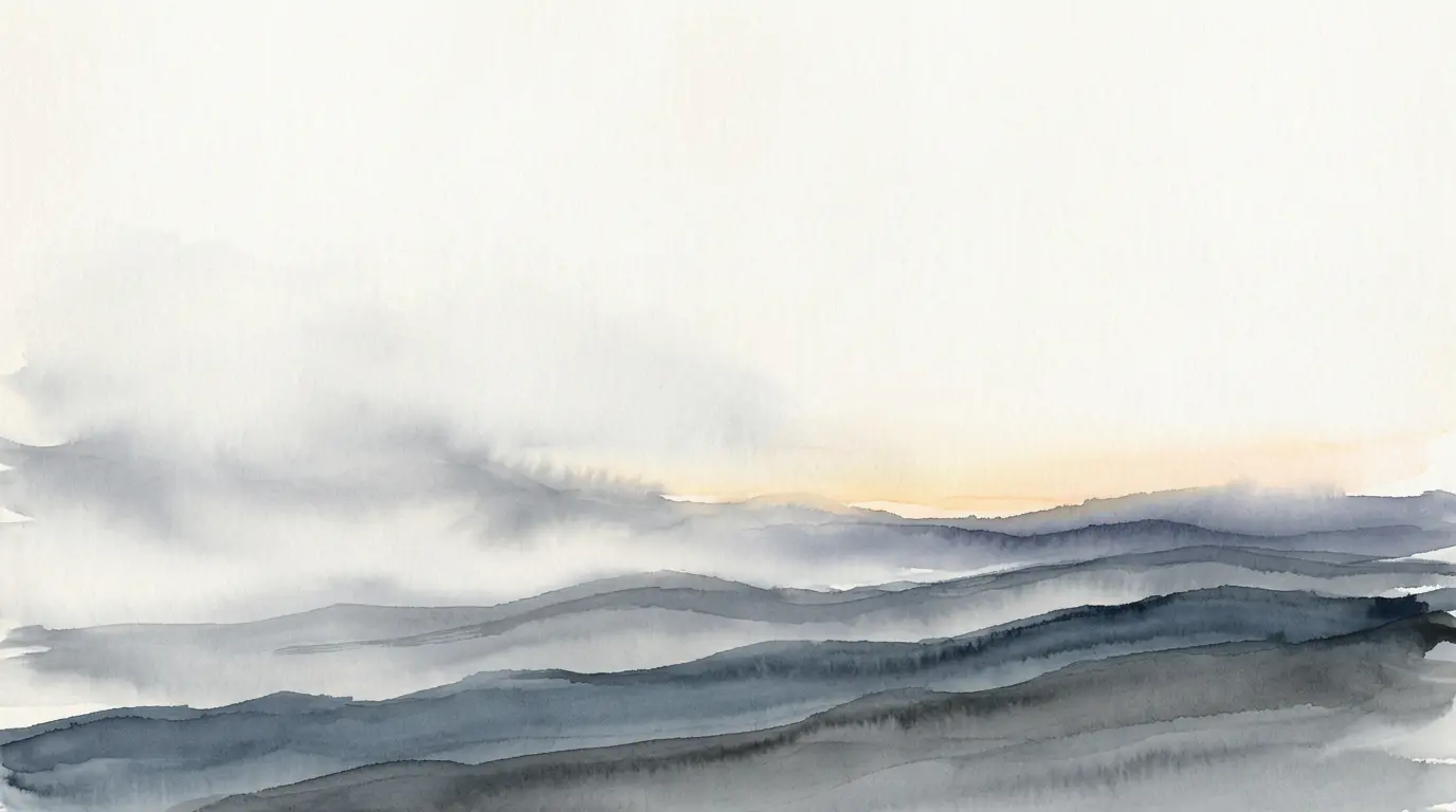 Fog over layered slate ridges, with a pale band of light at the horizon.